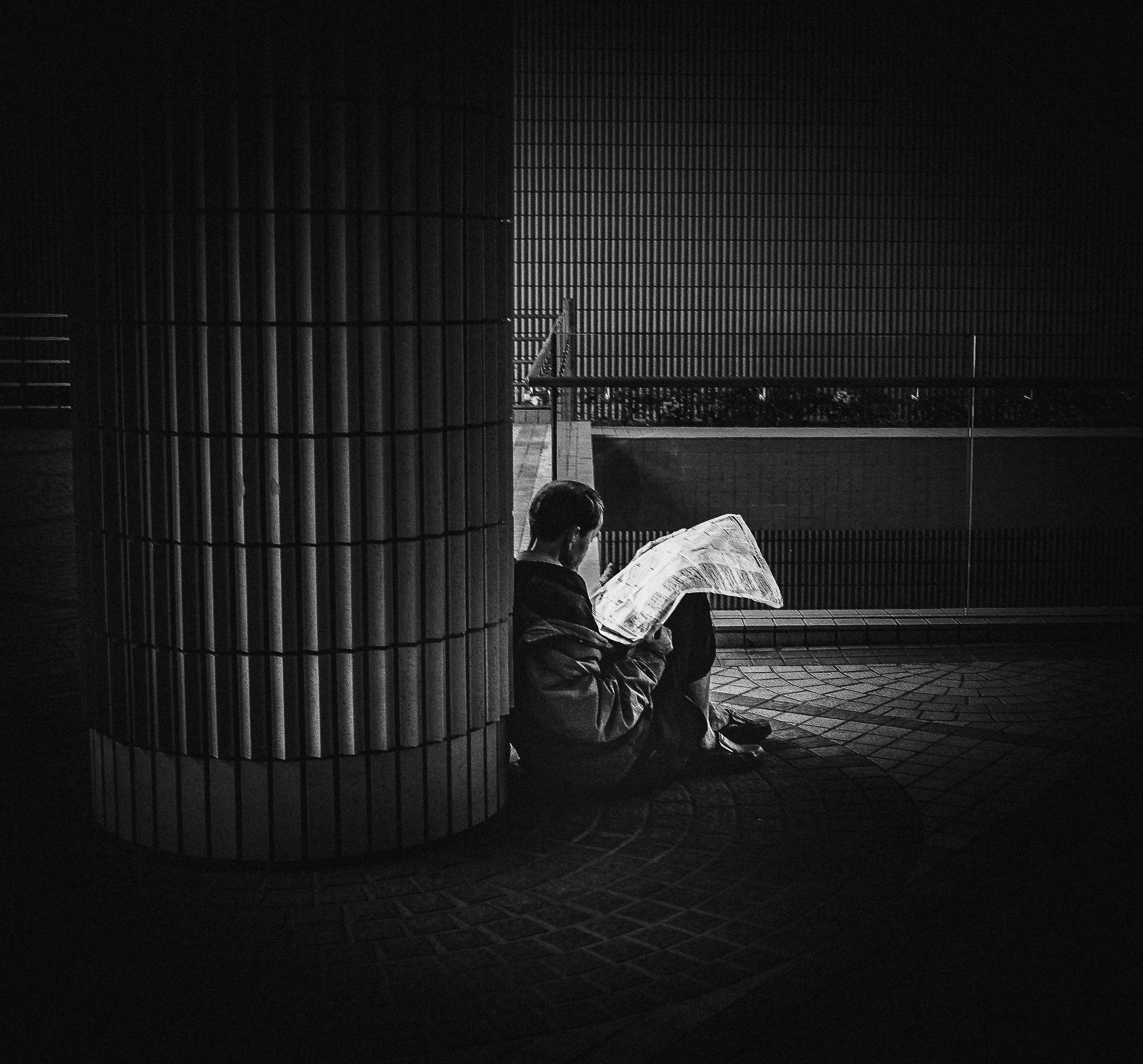 A person reading alone in a pool of city light