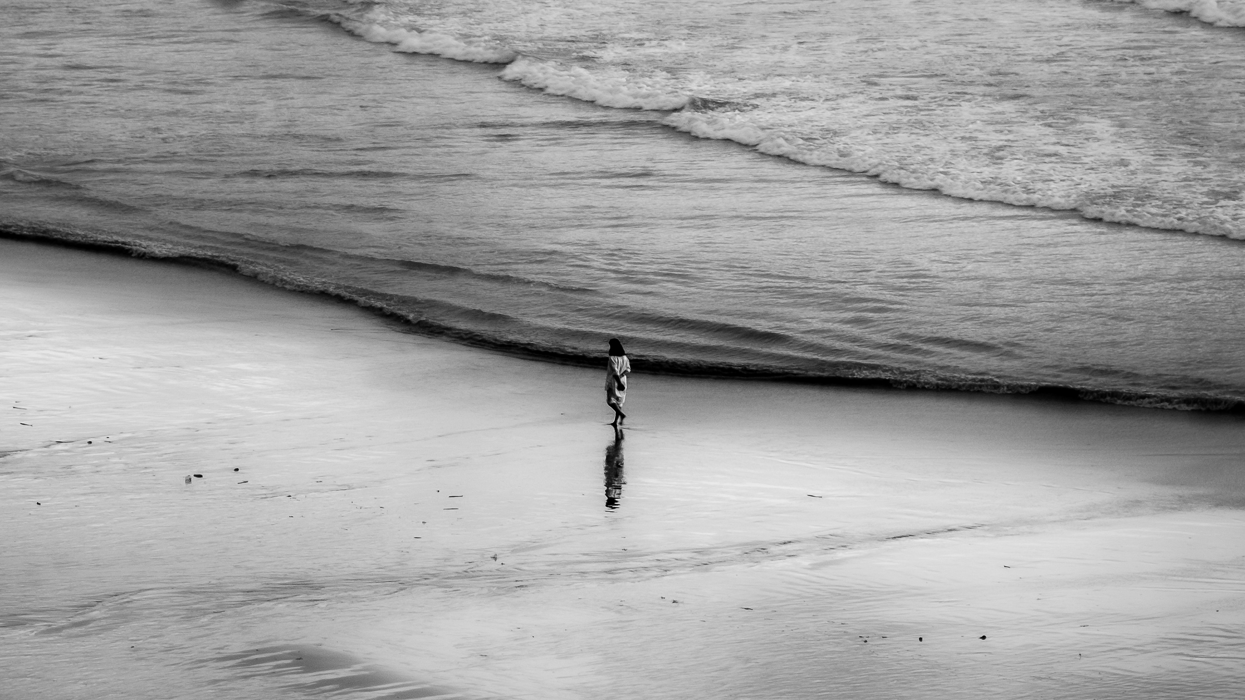 A solitary figure crossing an immense beach
